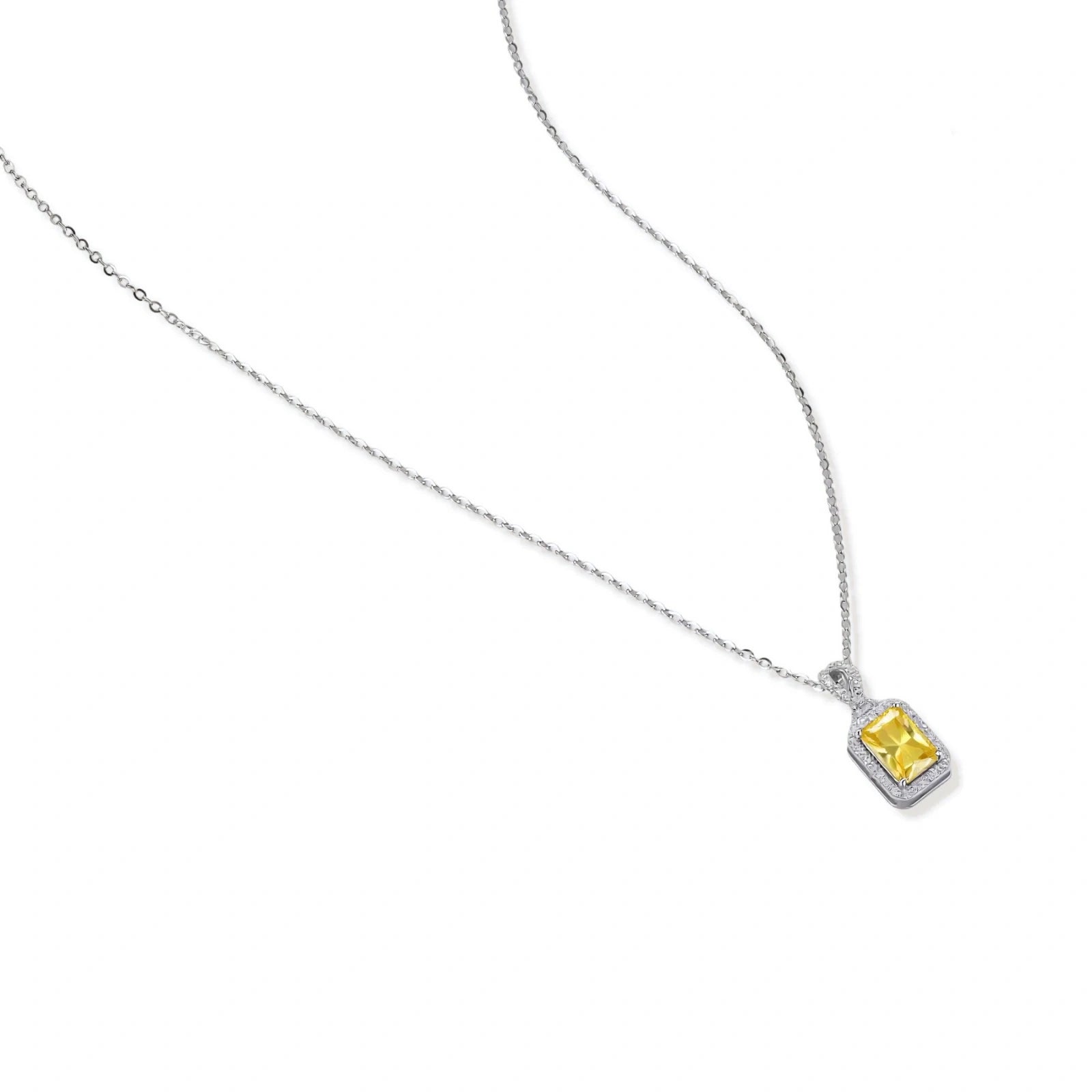 Rectangular yellow moissanite pendant in sterling silver halo setting on delicate chain against cream background.
