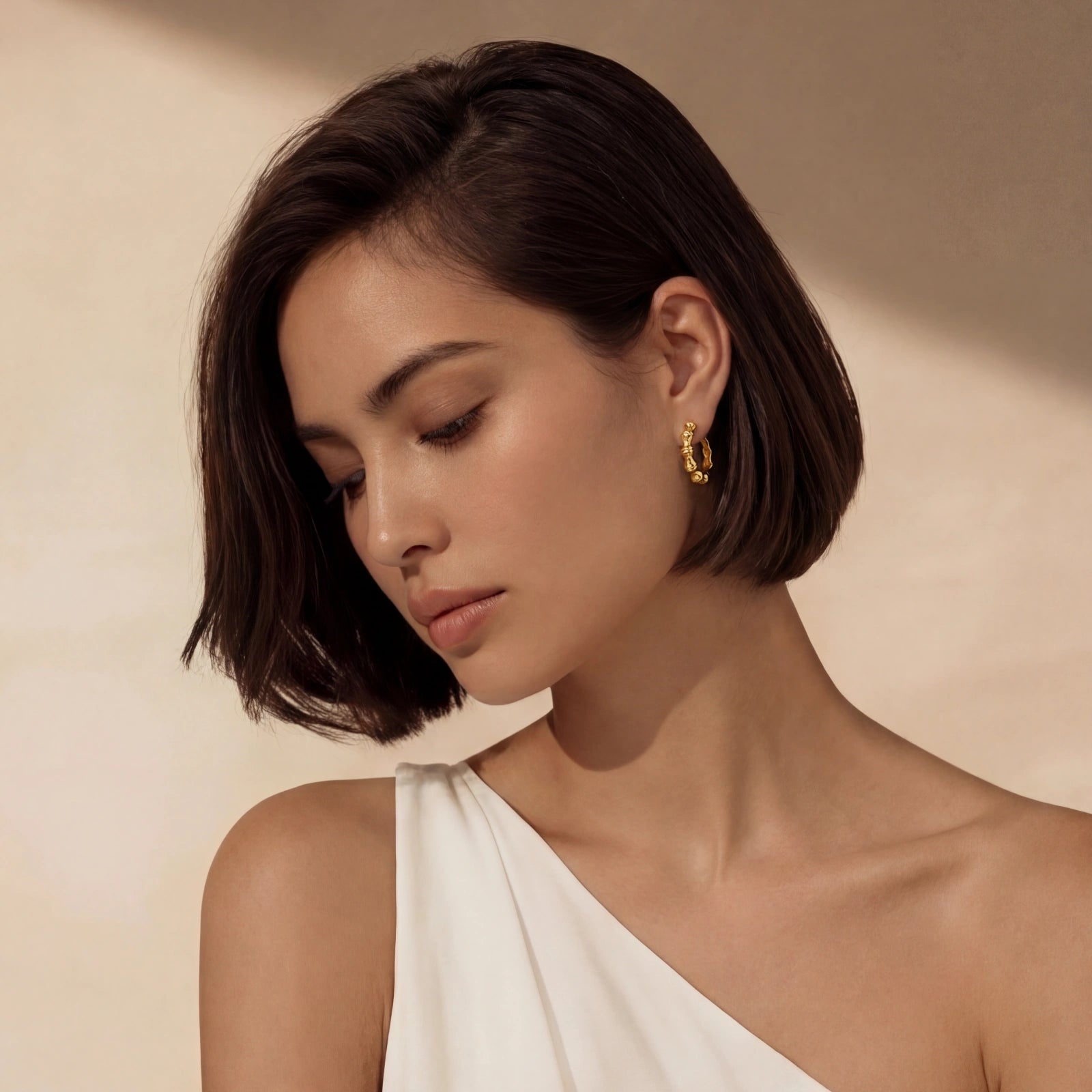 Elegant woman wearing AlbaLuxe Bamboo Segment Hoops, 14K gold plated hoop earrings with a bamboo-inspired design, styled with a white off-shoulder top against a neutral background.