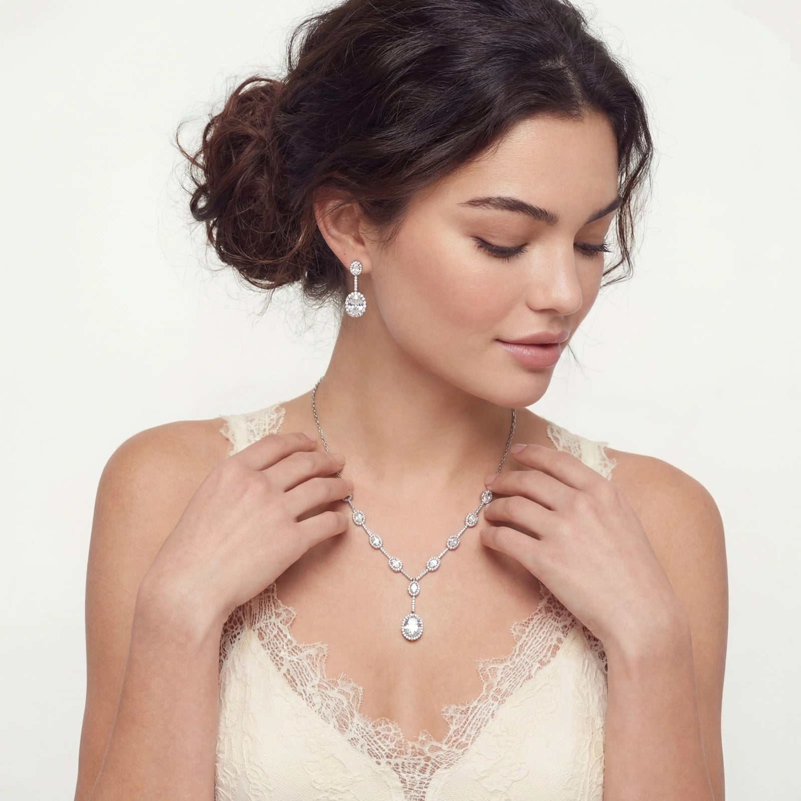 Woman wearing the Cascade Set featuring sterling silver necklace and matching earrings with round sparkling stones, styled with a lace-trimmed top.
