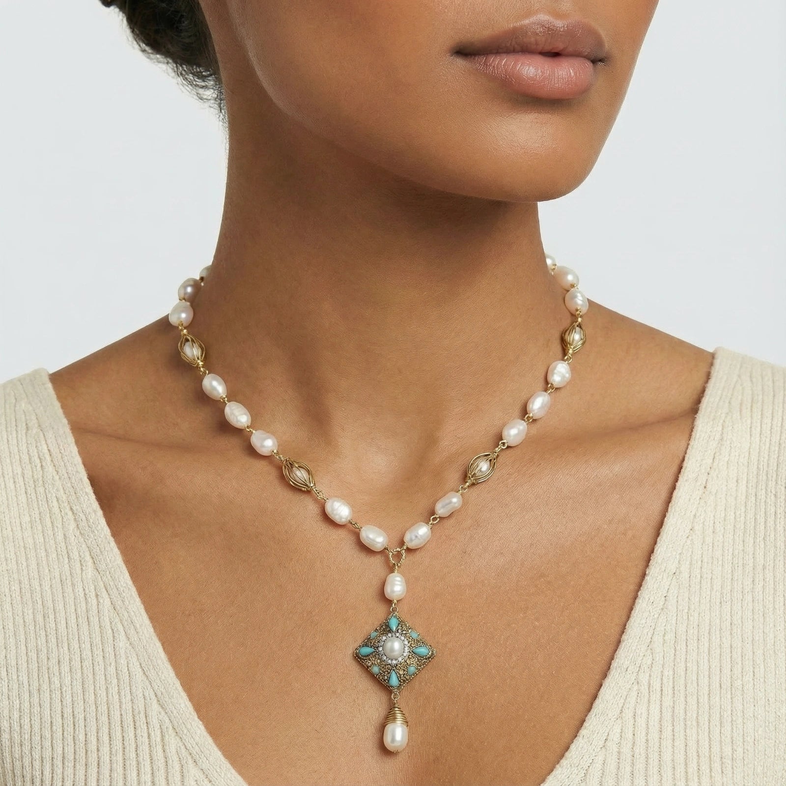 Pearl Drop Necklace featuring 14K gold plated accents with baroque pearls and a decorative turquoise and pearl pendant, styled on a model wearing a cream knit top.