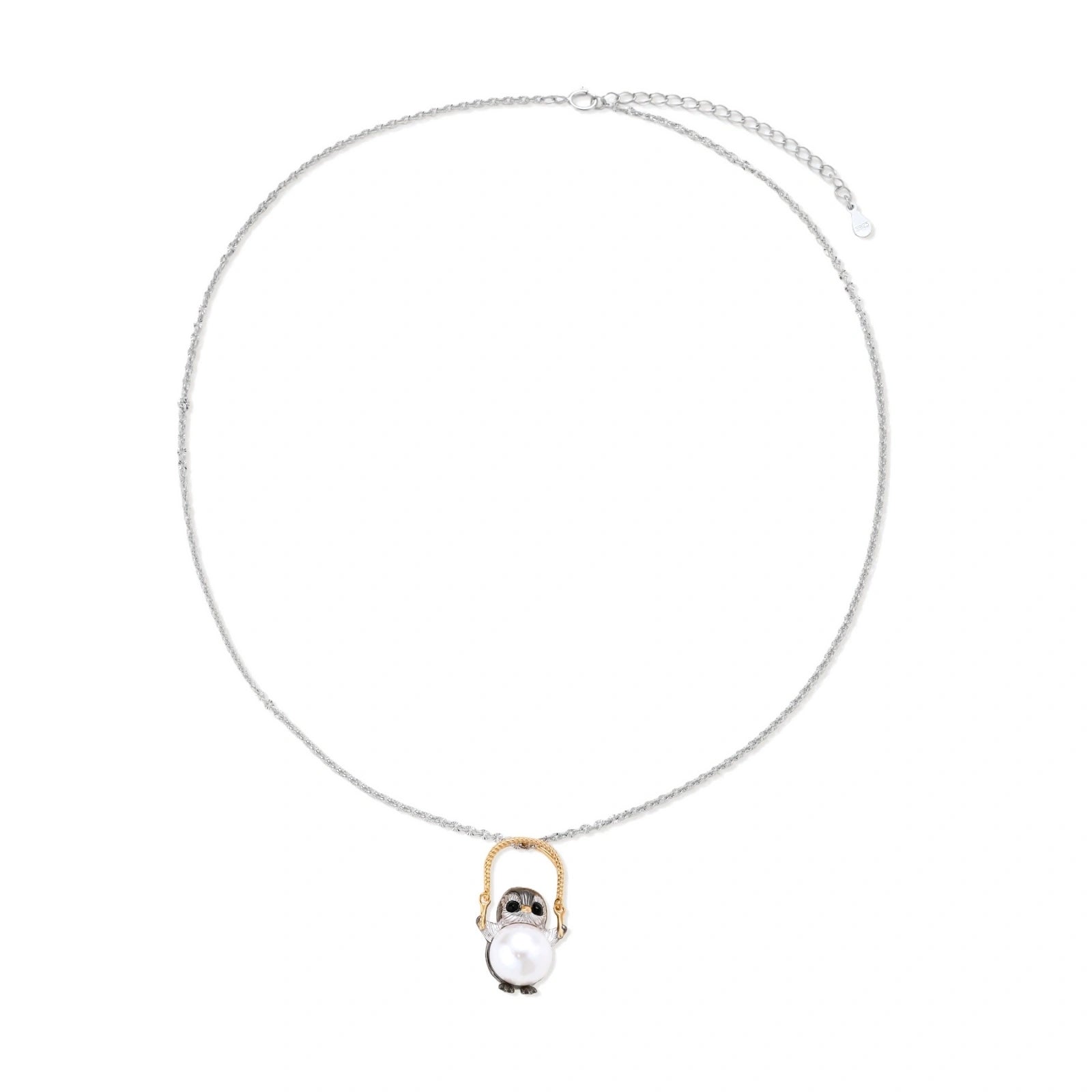 Whimsical penguin pendant holding a white pearl on a gold swing, rhodium-plated silver chain on cream background.