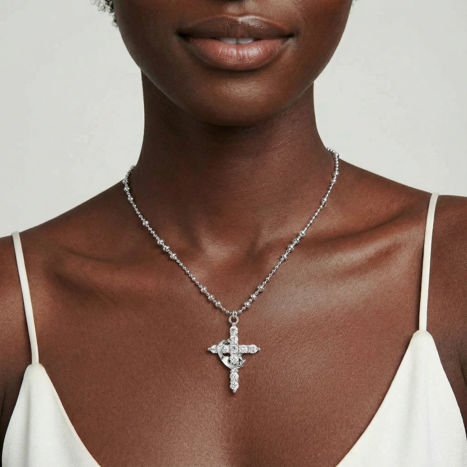 Grace Necklace featuring a delicate sterling silver chain and intricately designed pendant, styled elegantly on a model wearing a white sleeveless top.