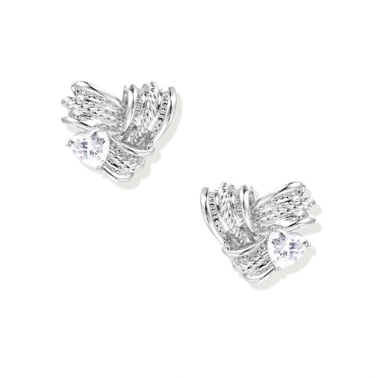 Pair of sculptural white gold-plated stud earrings with twisted ribbon design and sparkling zirconia stones on cream background