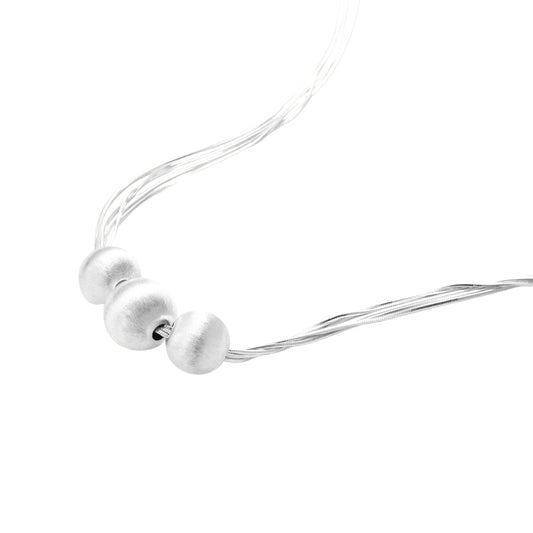 Sterling silver multi-strand necklace with three brushed round beads on cream background