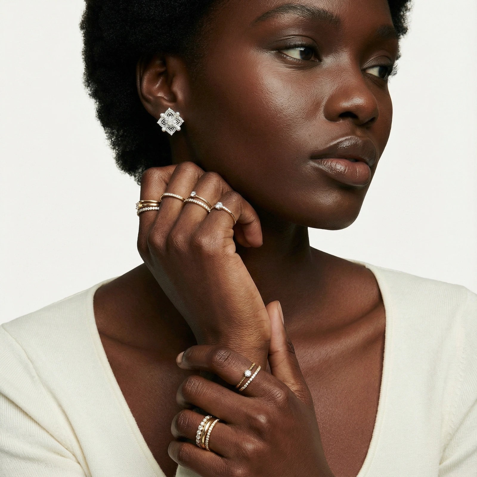 Close-up of a woman wearing elegant Pearl Studs with multiple gold plated and sterling silver rings, showcasing luxury jewellery from AlbaLuxe with ethically sourced materials.