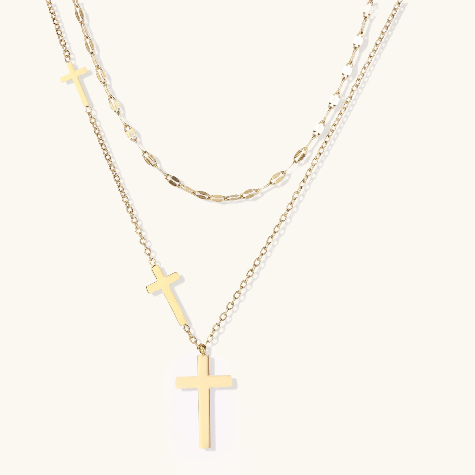 Three-layered gold necklace set with graduated  pendants in mixed chain styles on white background.