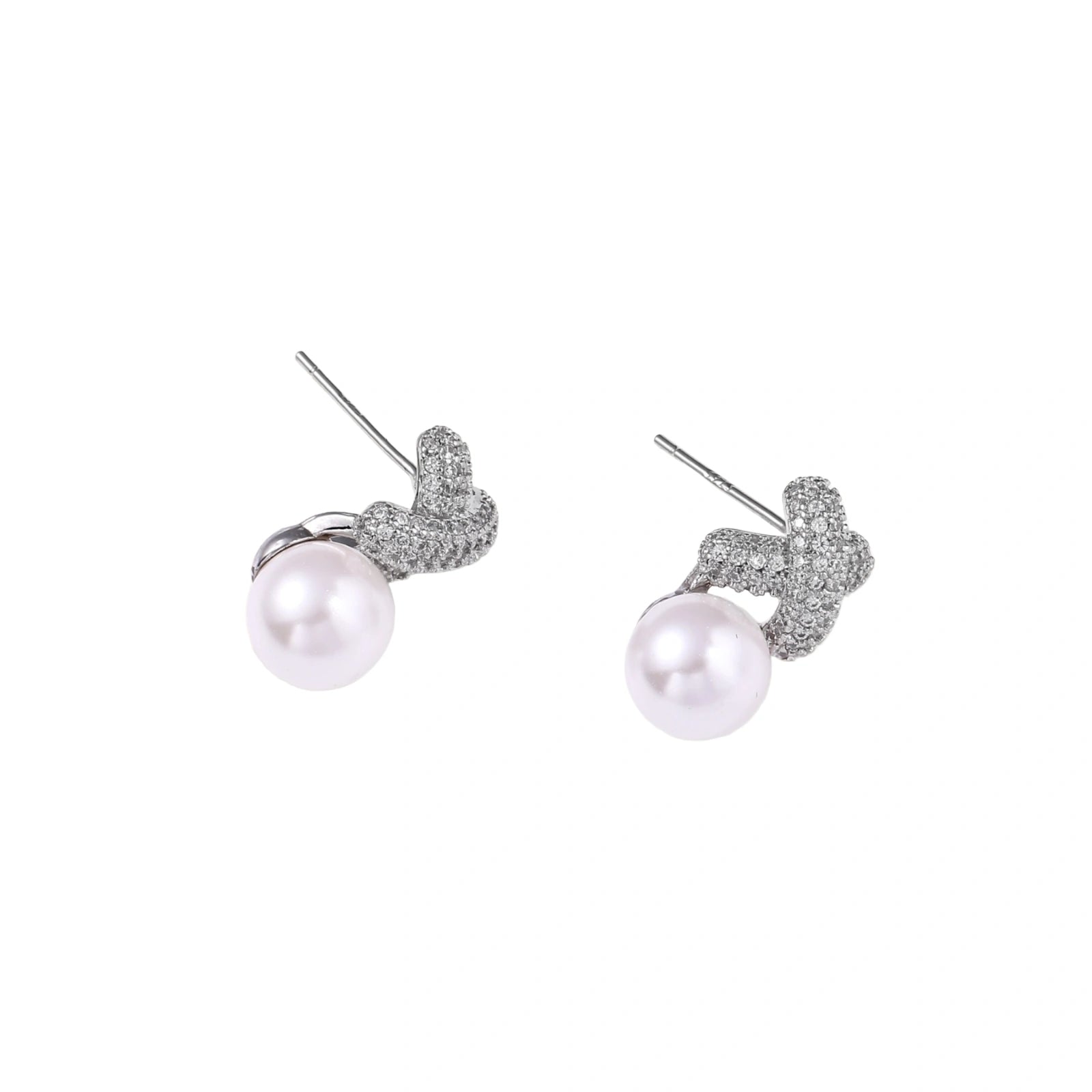 White gold plated studs featuring pavé X-shaped tops with freshwater pearl drops on cream background.