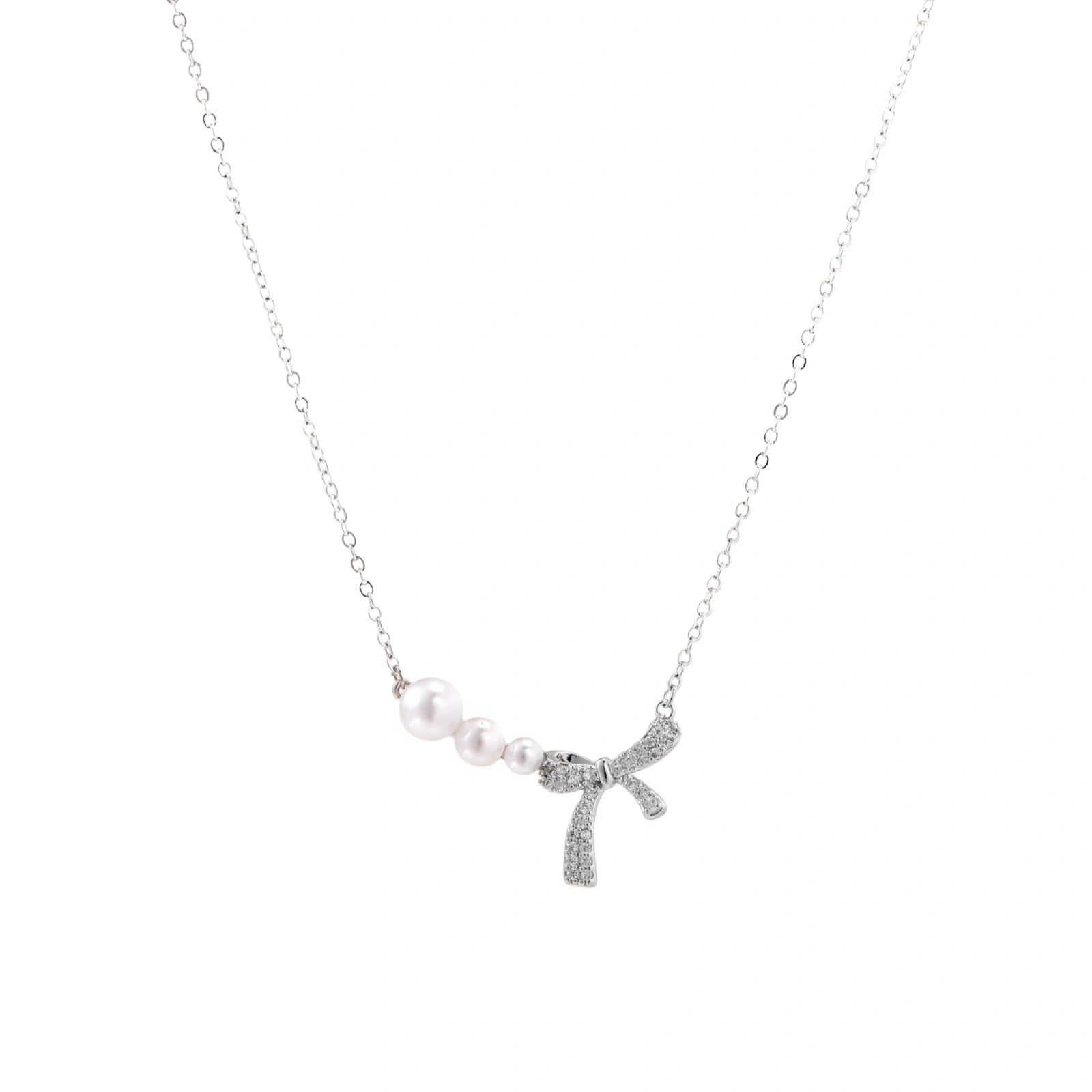 Delicate white gold plated necklace with freshwater pearls and sparkly crystal bow pendant on white background