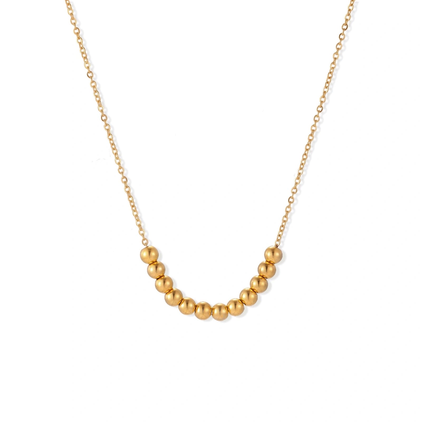 Delicate gold-plated necklace with graduated spherical beads forming gentle smile curve on beige background