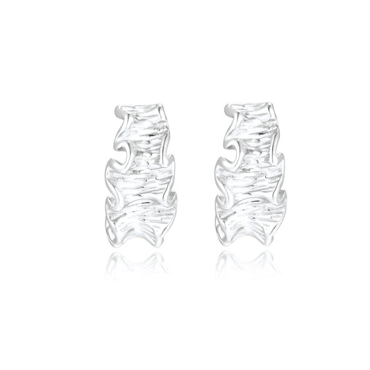 White gold plated sculptural hoop earrings with organic wavy edges and reflective metallic finish on cream background