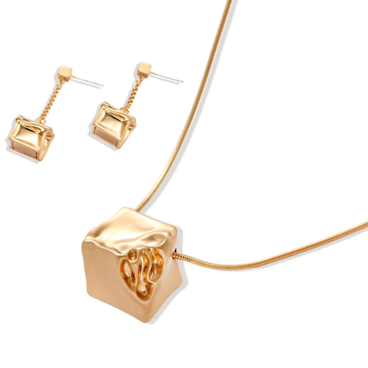 Modern geometric jewelry set featuring crumpled cube pendants in warm gold finish with chain details on beige background.