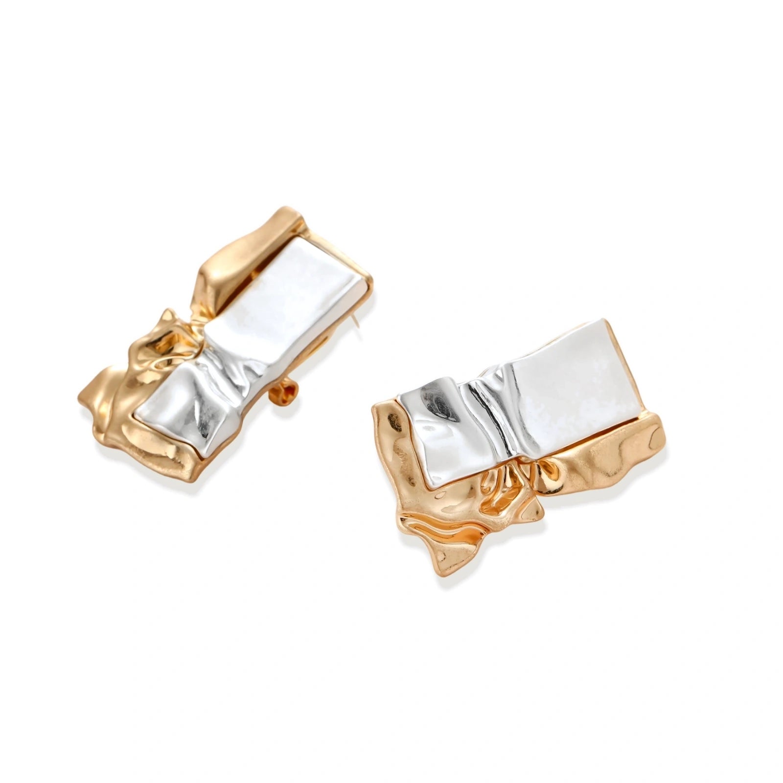 Close-up of avant-garde sculptural earrings with flowing liquid metal design in gold and silver tones on white background.