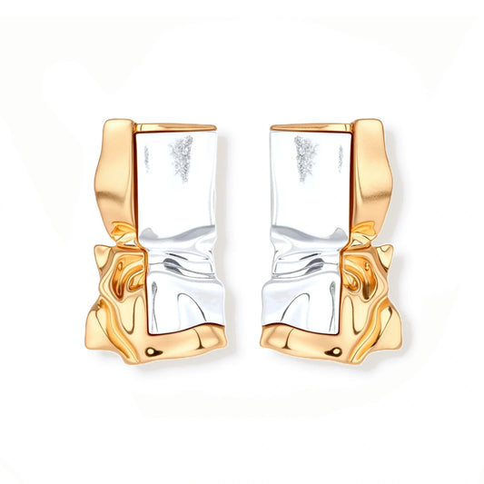 Close-up of avant-garde sculptural earrings with flowing liquid metal design in gold and silver tones on white background.