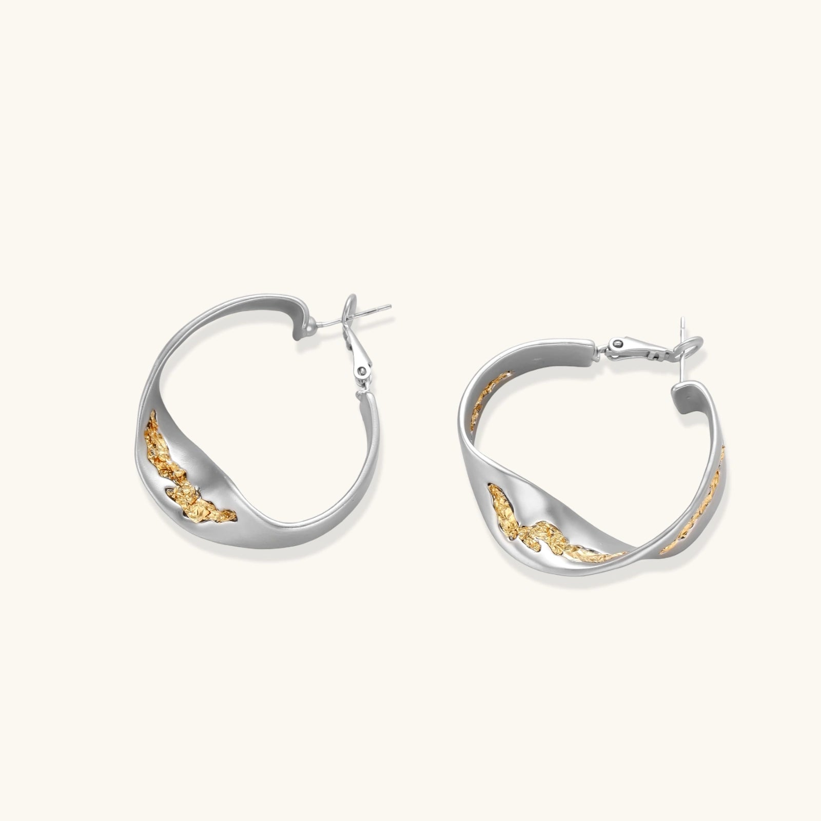 Sculptural wavy hoop earrings with crystal details and organic curved silhouette in gold and silver variants