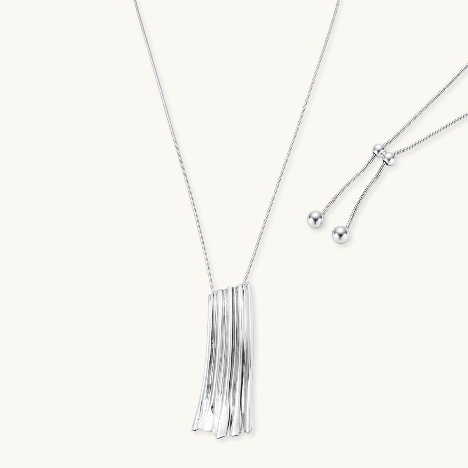 Modern adjustable necklace featuring geometric ribbed pendant with vertical lines in gold and silver finish options.