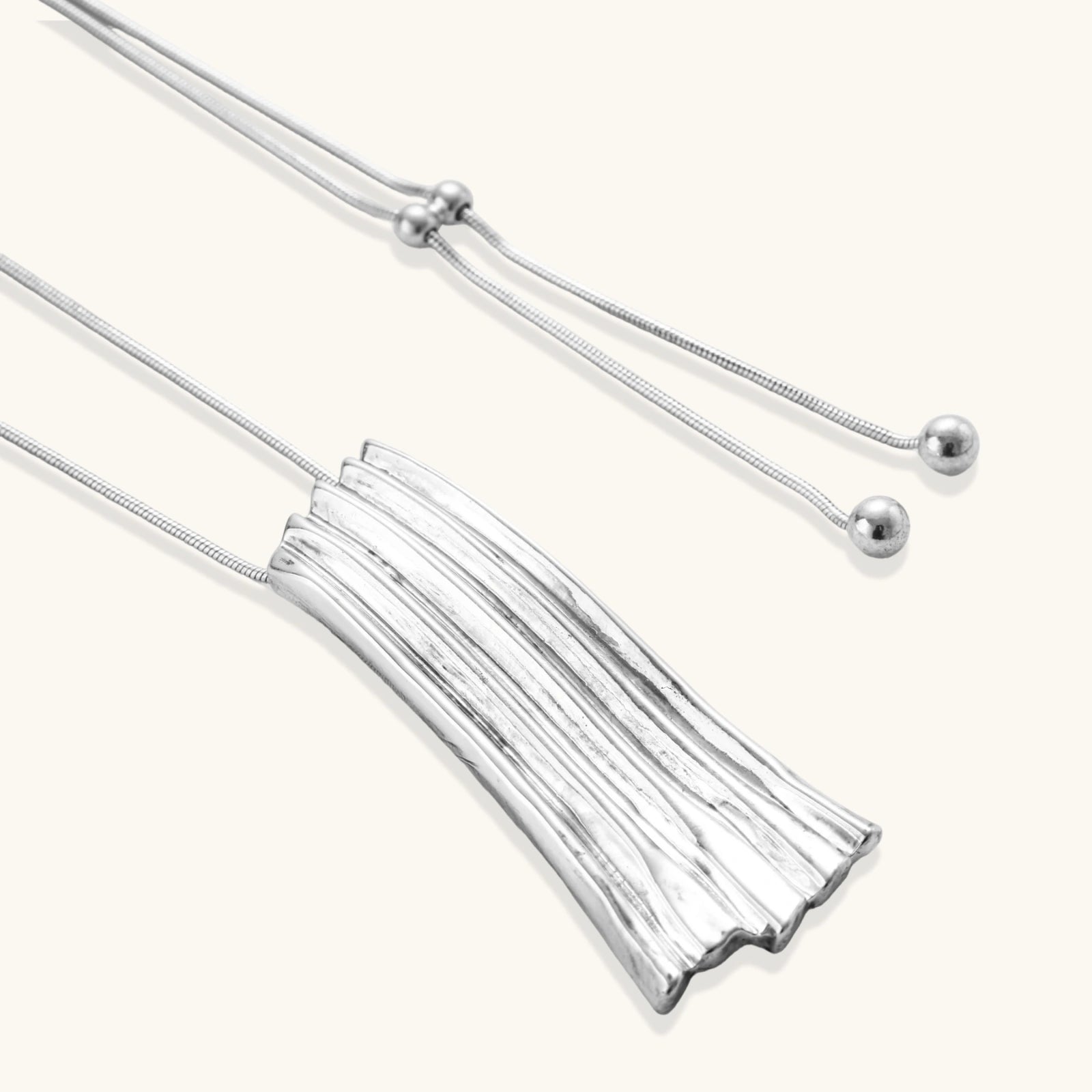 Modern adjustable necklace featuring geometric ribbed pendant with vertical lines in gold and silver finish options.