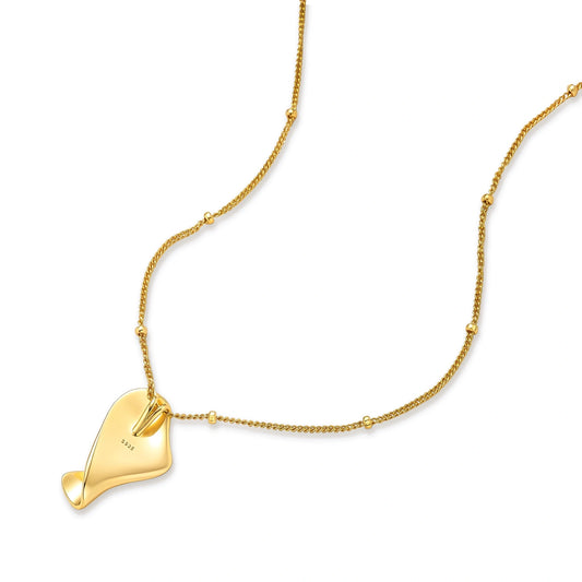 Gold-plated 925 sterling silver necklace with a twisted, fluid pendant and a beaded curb chain on a cream background.