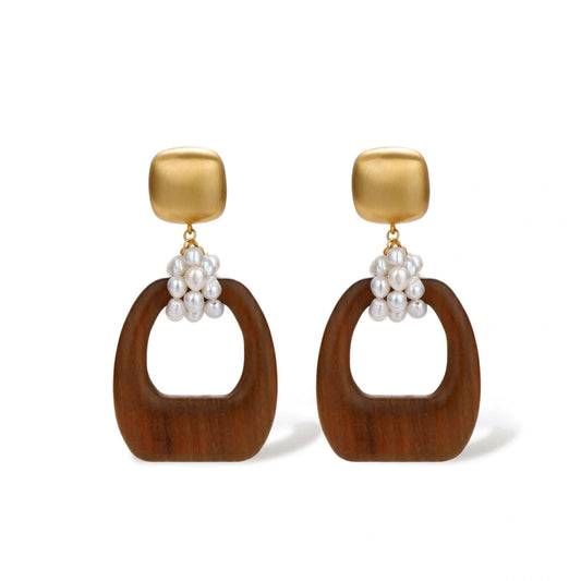 Gold-plated stud earrings with pearl clusters and organic brown wooden hoops on cream background