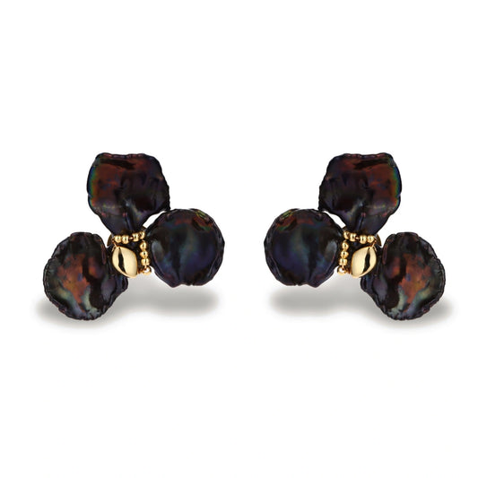 Dark iridescent baroque pearls arranged in flower pattern with 18K gold-plated center on cream background.